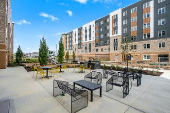 A patio with tables and chairs is in front of a building.
